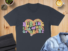 Load image into Gallery viewer, Dark t-shirt with retro rainbow text "Nursing is a work of heart" and flowers.