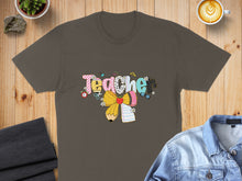 Load image into Gallery viewer, Brown t-shirt with "Teacher" graphic featuring colorful letters, pencil, and bows.