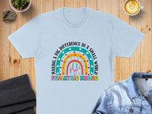 Load image into Gallery viewer, Light blue t-shirt with "Making a Big Difference in a Small World Pediatric Nurse" text and rainbow design.