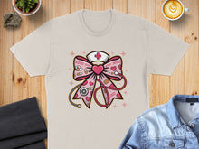 Load image into Gallery viewer, Pink bow with stethoscope, heart, and XOXO pattern on a t-shirt.