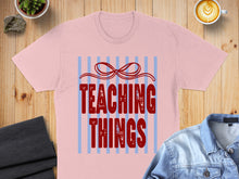 Load image into Gallery viewer, Pink t-shirt with "TEACHING THINGS" in red text and a blue striped bow.