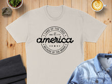 Load image into Gallery viewer, Cream t-shirt with "Land of the Free, Because of the Brave" text.
