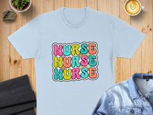 Load image into Gallery viewer, Light blue t-shirt with colorful "NURSE" text in a wavy, retro font.