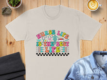 Load image into Gallery viewer, "Nurse life is the best life" text with medical icons on a tan t-shirt.