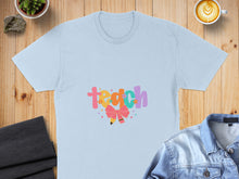 Load image into Gallery viewer, Light blue t-shirt with "teach" in colorful, whimsical letters and a pencil graphic.