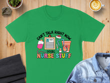 Load image into Gallery viewer, Green t-shirt with "Can't talk right now, doing nurse stuff" and medical icons.