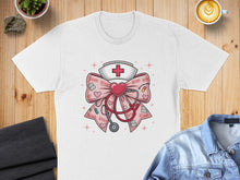 Load image into Gallery viewer, White t-shirt featuring a pink ribbon with XOXO pattern, stethoscope, and nurse hat.