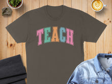 Load image into Gallery viewer, Brown t-shirt with "TEACH" in colorful block letters.