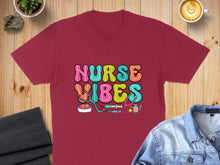 Load image into Gallery viewer, Burgundy t-shirt with "Nurse Vibes" text and medical icons.