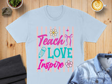 Load image into Gallery viewer, Light blue t-shirt with "Teach Love Inspire" text and floral design.