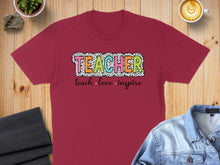 Load image into Gallery viewer, Maroon t-shirt with "TEACHER" in colorful block letters and "teach love inspire" below.