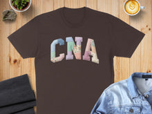 Load image into Gallery viewer, Brown t-shirt with "CNA" spelled out in a patchwork of colorful fabrics.
