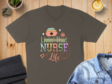 Load image into Gallery viewer, T-shirt with colorful text "Livin' That Nurse Life" and nurse-themed graphics.