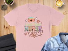 Load image into Gallery viewer, Pink t-shirt with "Livin' That Nurse Life" text and stethoscope graphic.