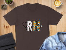 Load image into Gallery viewer, Brown t-shirt with "RN" in a Halloween-themed design featuring a stethoscope and eyes.