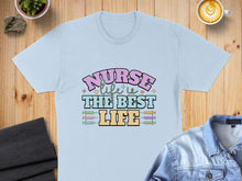 Load image into Gallery viewer, Light blue t-shirt with "Nurse is the best life" text and colorful syringe graphics.