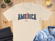 Load image into Gallery viewer, Cream t-shirt with "America" and lightning bolt graphic.