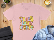 Load image into Gallery viewer, Pink t-shirt with "Teach Love Inspire" text in colorful, retro lettering.