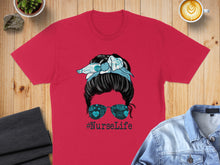 Load image into Gallery viewer, Red t-shirt with messy bun, sunglasses, and #NurseLife text.