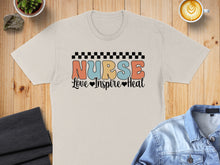 Load image into Gallery viewer, Cream t-shirt with "Nurse Love Inspire Heal" text, checkered border.