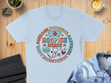 Load image into Gallery viewer, Light blue t-shirt with circular nurse design featuring "COURAGE. PATIENCE. COMPASSION. LOVE. NURSE LIFE. CAFFEINE."