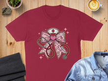 Load image into Gallery viewer, Burgundy t-shirt with pink nurse-themed graphic of a bow with stethoscope and heart icons.