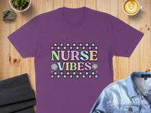 Load image into Gallery viewer, Purple t-shirt with "Nurse Vibes" text in pastel checkerboard and floral design.