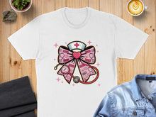 Load image into Gallery viewer, Pink bow with stethoscope, nurse hat, and XOXO pattern on a white t-shirt.