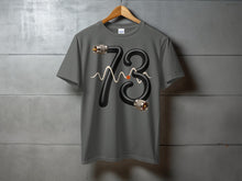 Load image into Gallery viewer, Grey t-shirt with black number 73 graphic made of hose and connectors.