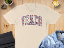 Load image into Gallery viewer, T-shirt with "TEACH" text featuring a floral pattern on a wooden surface.