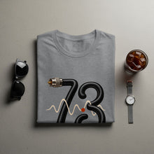 Load image into Gallery viewer, Gray t-shirt with black cable art forming "73" and wavy lines.