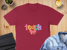 Load image into Gallery viewer, Maroon t-shirt with "Teach" in colorful cartoon letters and a bow.