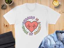 Load image into Gallery viewer, White t-shirt with "Nursing is a Work of Heart" graphic and EKG line.