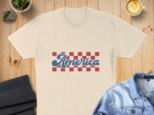 Load image into Gallery viewer, Cream t-shirt with "America" in red and blue script on a blue and red checkered background.