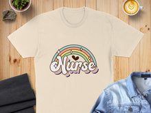 Load image into Gallery viewer, Cream t-shirt with "Nurse" text and pastel rainbow design.