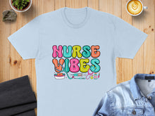 Load image into Gallery viewer, Light blue t-shirt with colorful "Nurse Vibes" text and medical icons.