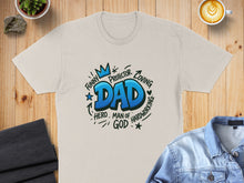 Load image into Gallery viewer, Cream t-shirt with blue "DAD" graphic and surrounding words like "FUNNY," "LOVING," and "HERO."