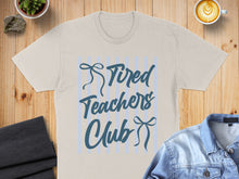 Load image into Gallery viewer, Light beige t-shirt with "Tired Teachers Club" text and bow graphic.