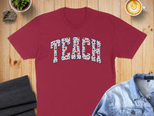 Load image into Gallery viewer, Burgundy t-shirt with "TEACH" spelled out in floral and star patterns.