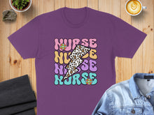 Load image into Gallery viewer, Purple t-shirt with "NURSE" text in colorful lightning bolt and floral designs.
