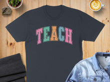 Load image into Gallery viewer, Dark grey t-shirt with "TEACH" in colorful, distressed block letters.