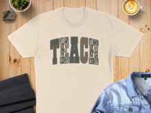 Load image into Gallery viewer, Cream t-shirt with "TEACH" in camouflage letters, laid flat.