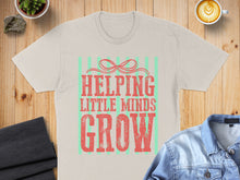 Load image into Gallery viewer, Cream t-shirt with "Helping Little Minds Grow" in red text.