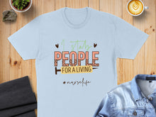 Load image into Gallery viewer, Light blue t-shirt with "I stab people for a living" text and "#nurselife".