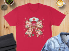 Load image into Gallery viewer, Red t-shirt with a nurse's hat and stethoscope forming a bow with hearts.