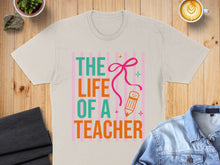 Load image into Gallery viewer, T-shirt with "The Life of a Teacher" text, pencil, and pink ribbon graphic.