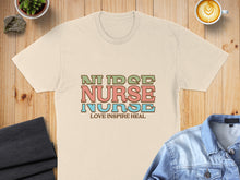 Load image into Gallery viewer, Cream t-shirt with "Nurse Love Inspire Heal" text in colorful block letters.