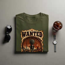 Load image into Gallery viewer, Olive green t-shirt featuring a "WANTED" graphic with a microphone and desert scene.