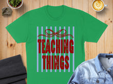 Load image into Gallery viewer, Green t-shirt with red text "TEACHING THINGS" and striped background.