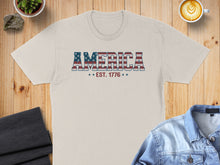 Load image into Gallery viewer, T-shirt with "AMERICA EST. 1776" in stars and stripes lettering.